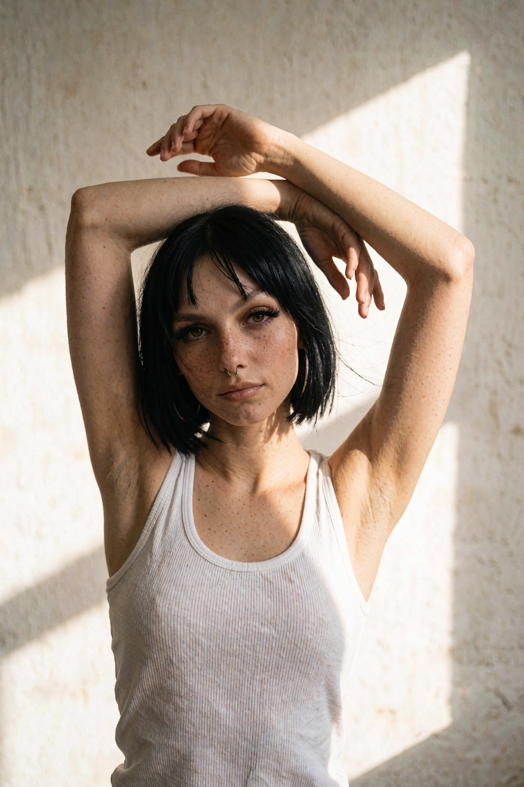 Gloria in a white tank top with arms raised in sunlight.