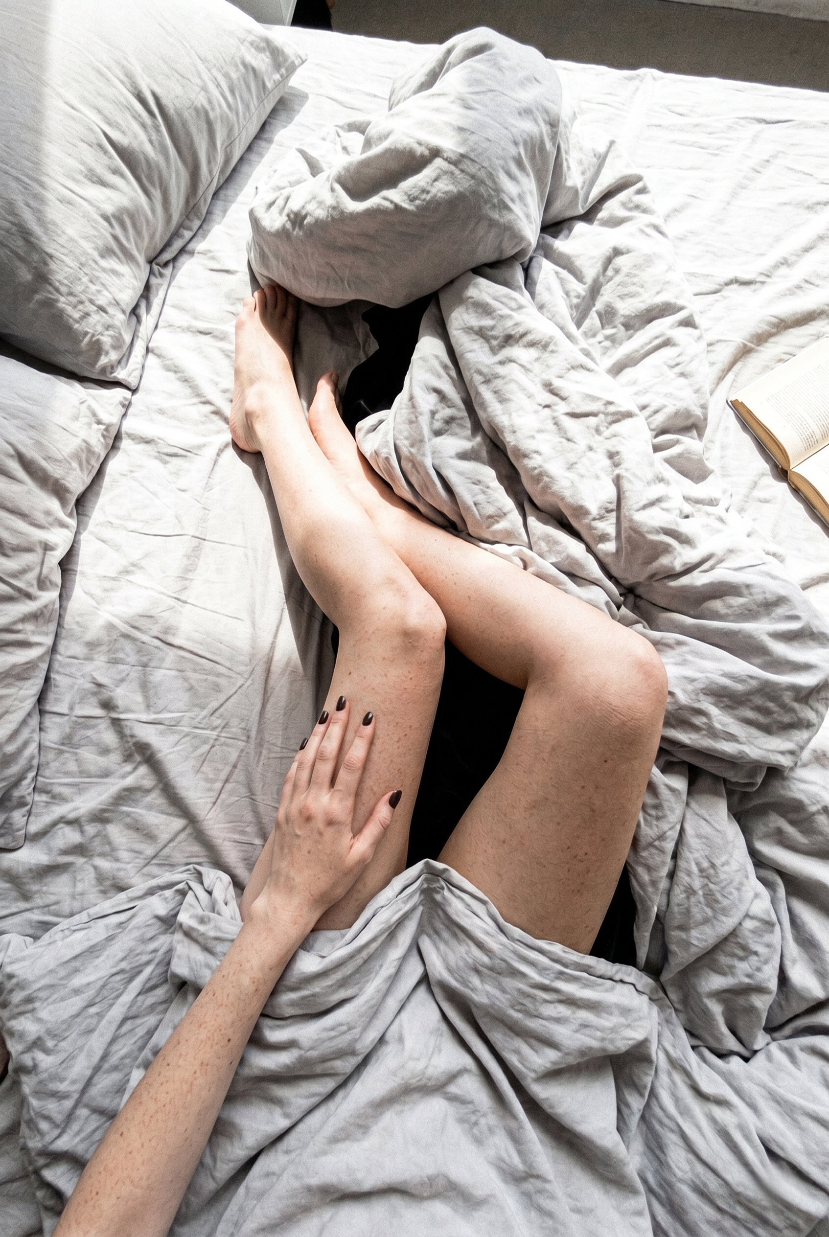 A quiet moment with a book and grey bed linen.